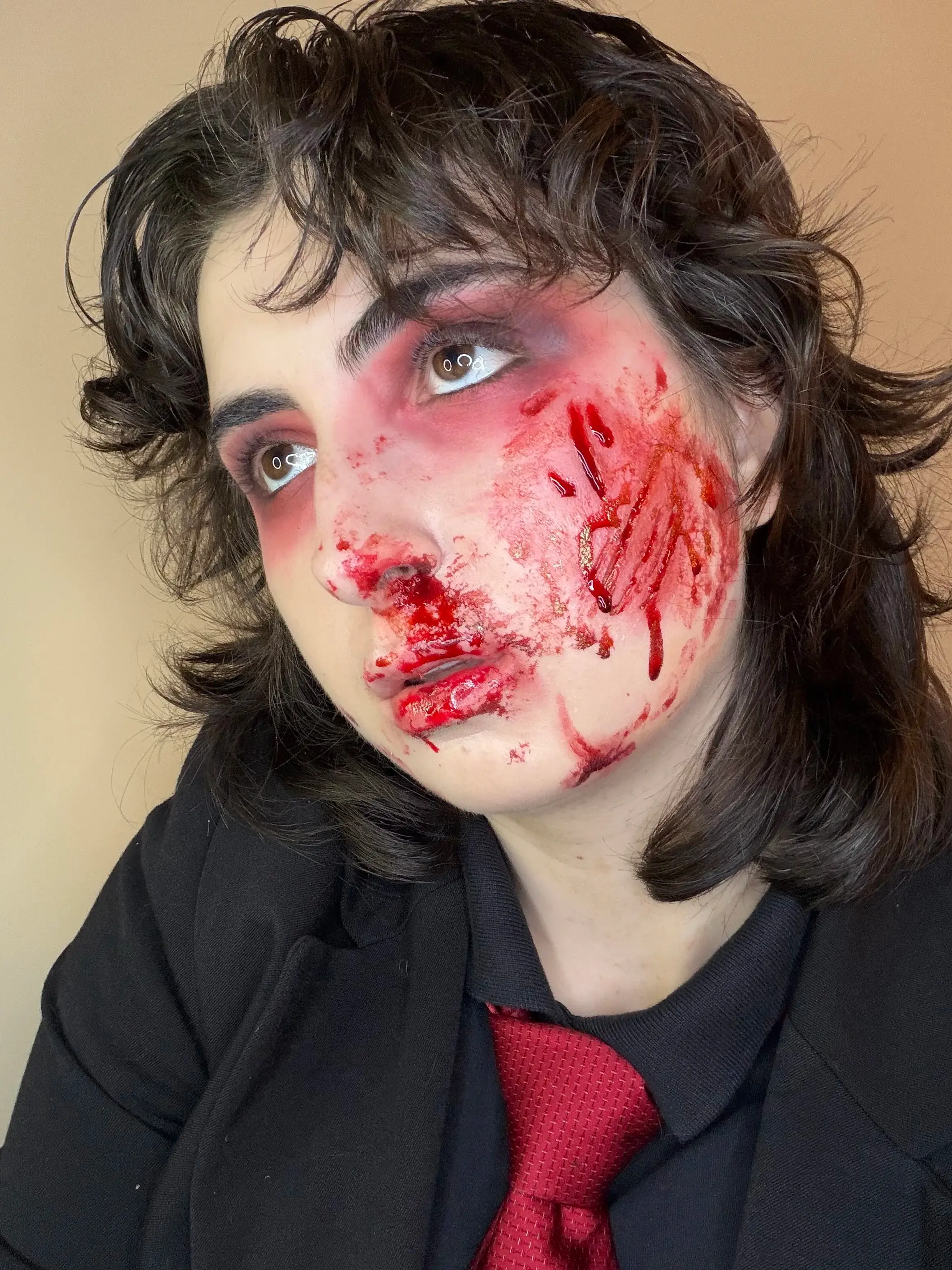 Raw, bloody wound across the cheek and jaw of a figure in a suit and red tie
