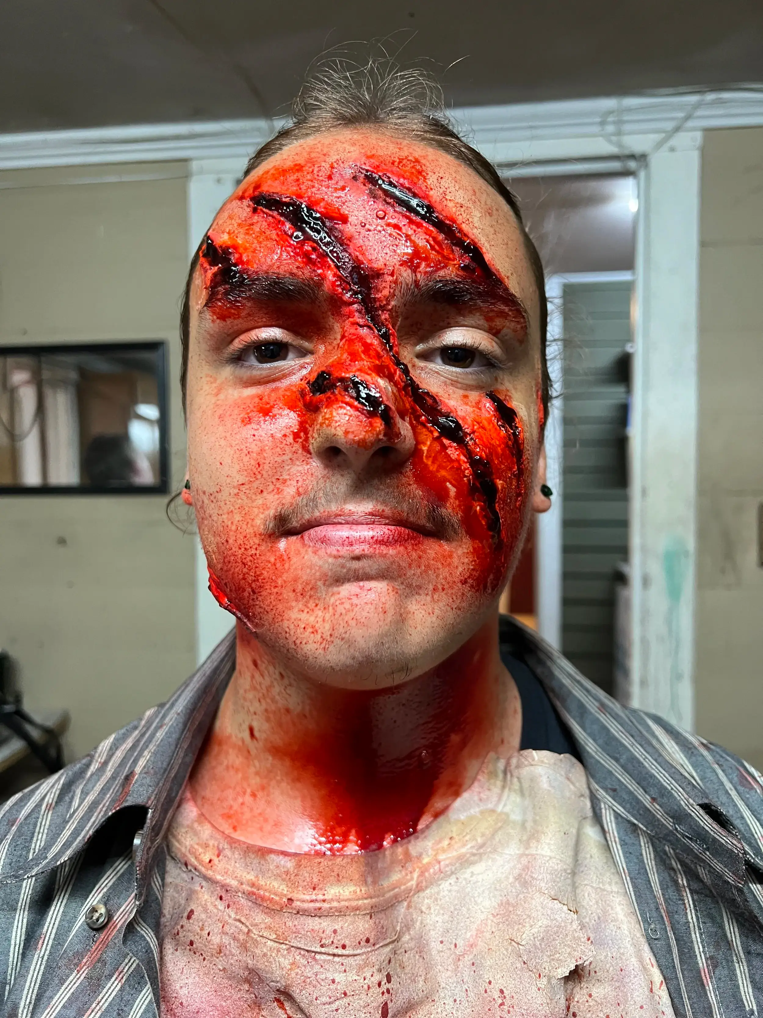 Face painted red with black claw slashes across it and a blood-soaked neck