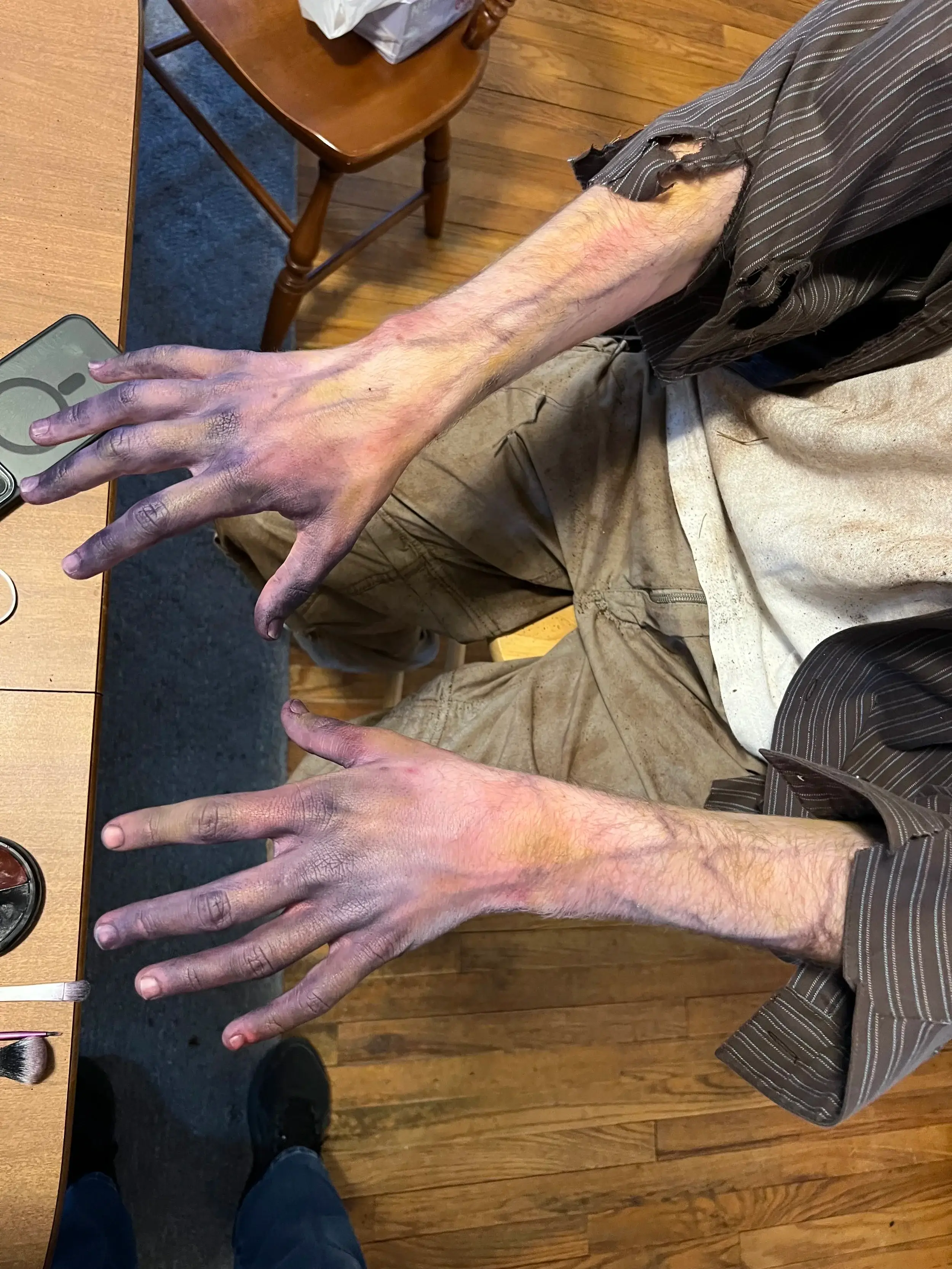 Pair of grey, veined, corpse-like hands resting on a table