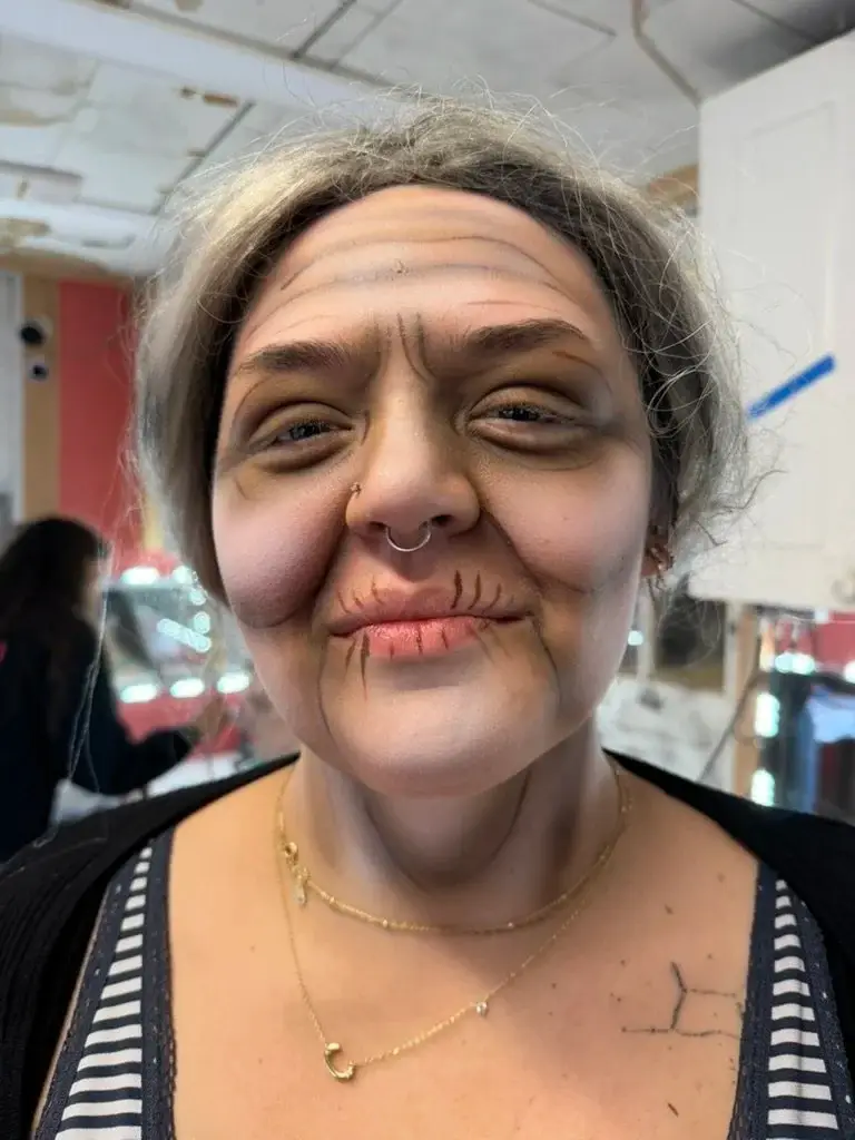 Old-age makeup with deep wrinkles, sunken eyes and a grey wig