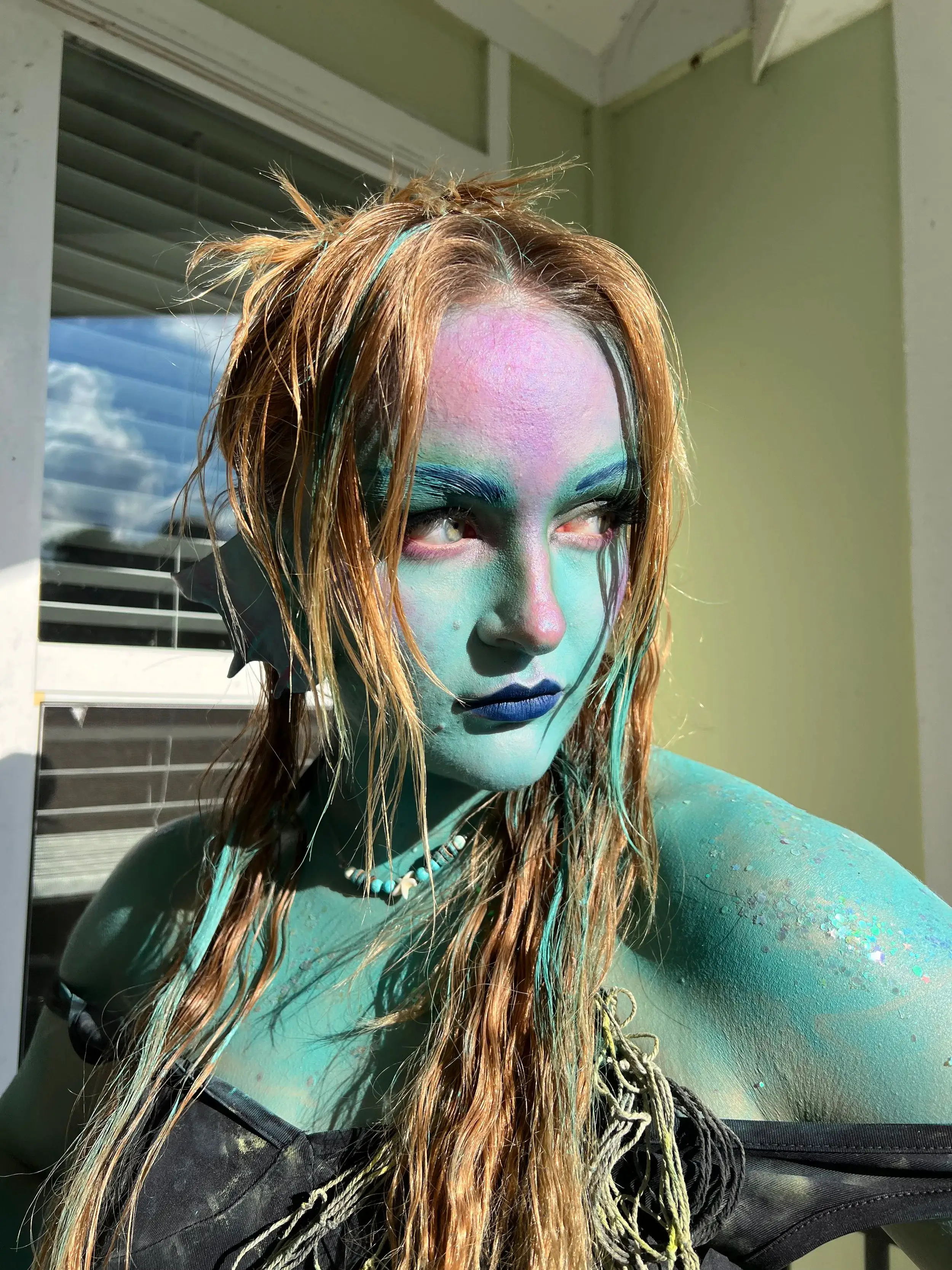 Sea creature with blue-green airbrushed skin across face, neck and shoulders, and matted rope-like hair