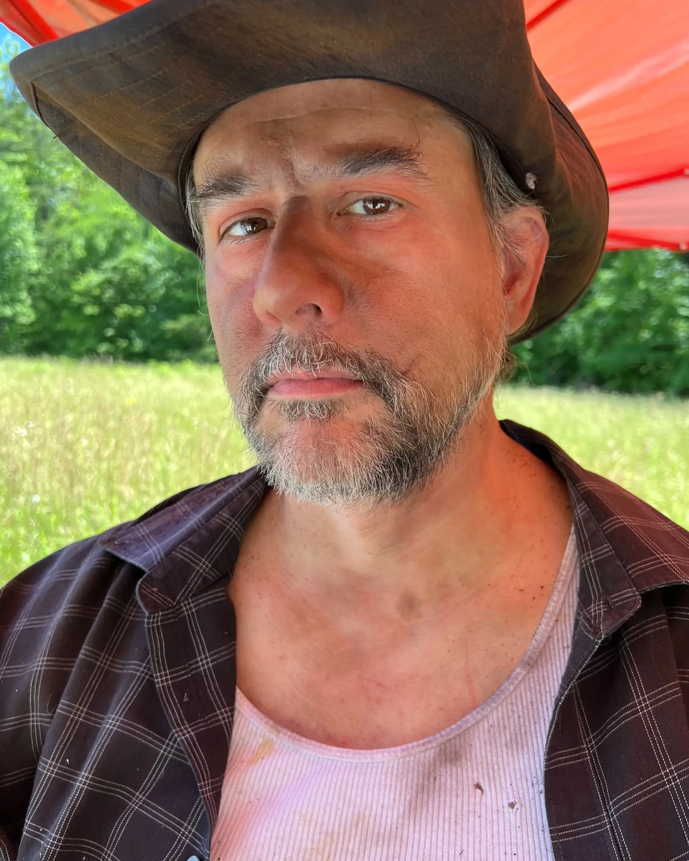 Weathered, sunburnt and dirt-streaked face under a wide-brimmed hat