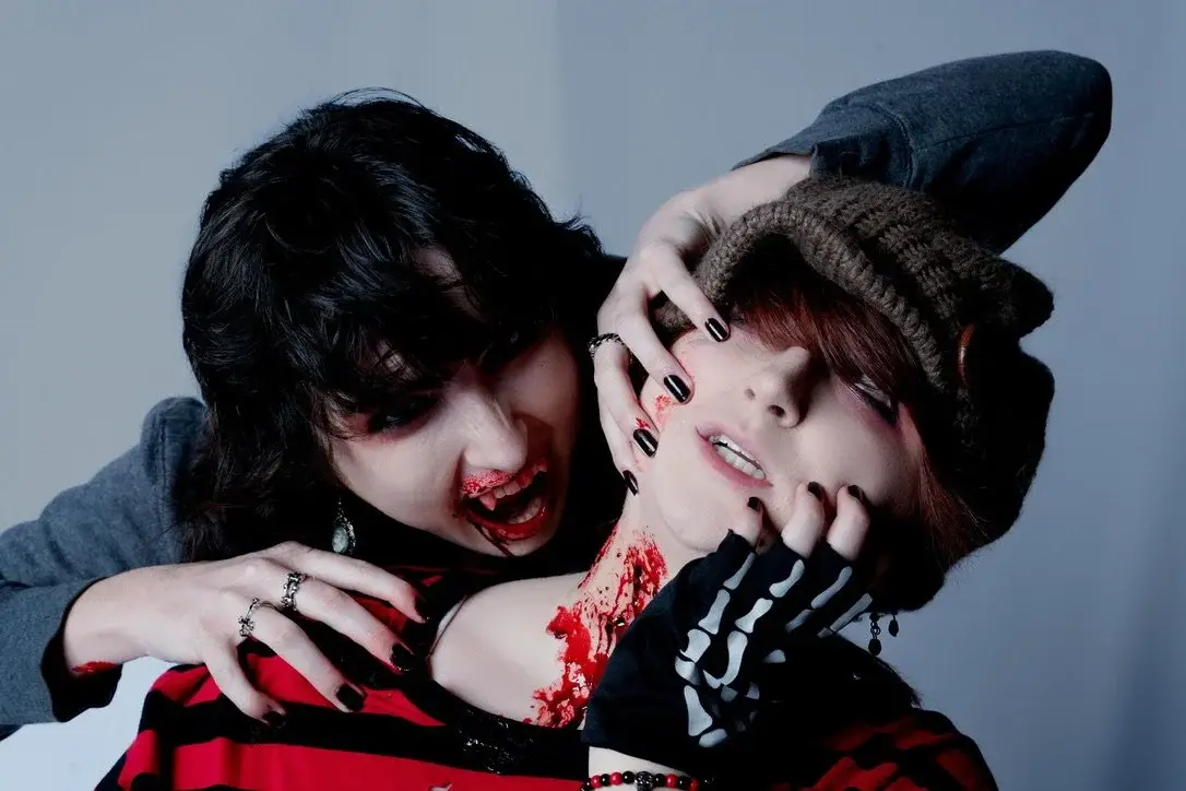 One vampire gripping another by the head, fangs bared over a bloodied neck